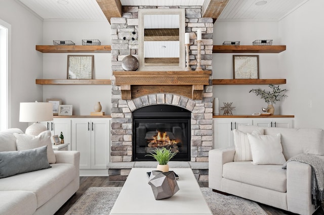 living room with beam ceiling, wooden ceiling, a stone fireplace, crown molding, and hardwood / wood-style floors