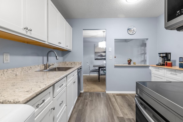 kitchen featuring wood-type flooring, a textured ceiling, white cabinetry, and sink