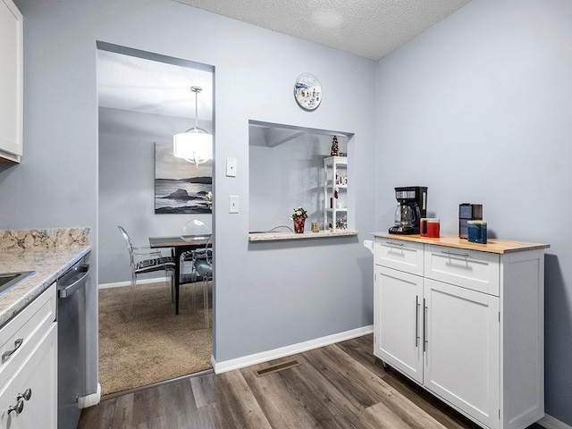 kitchen featuring white cabinetry, stainless steel dishwasher, dark hardwood / wood-style floors, decorative light fixtures, and a textured ceiling