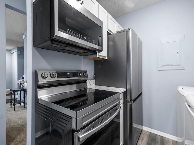 kitchen with electric panel, white cabinets, dark hardwood / wood-style floors, a textured ceiling, and stainless steel appliances