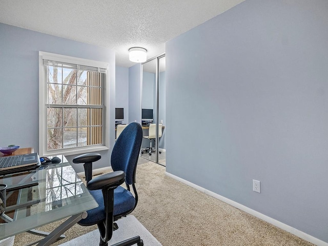 carpeted office space featuring a textured ceiling