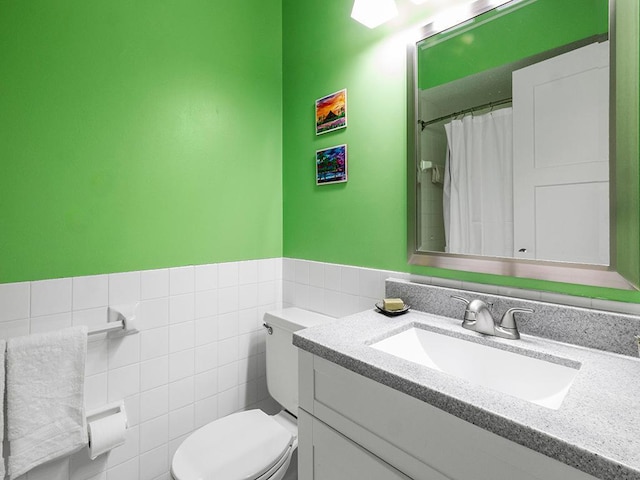 bathroom with walk in shower, vanity, toilet, and tile walls