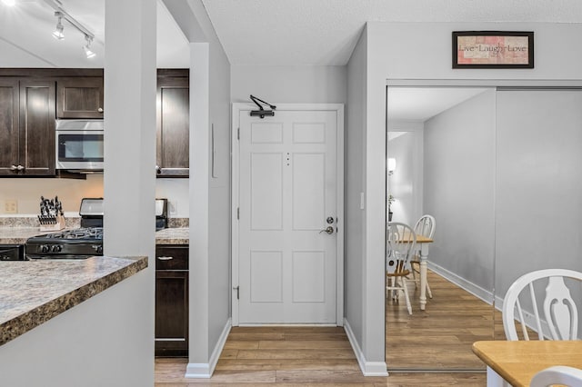 kitchen with black stove, stove, dark brown cabinets, a textured ceiling, and light hardwood / wood-style flooring