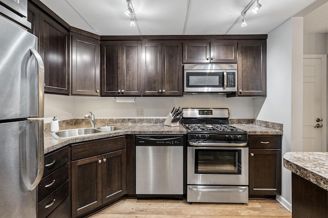 kitchen with sink, dark brown cabinets, track lighting, and appliances with stainless steel finishes