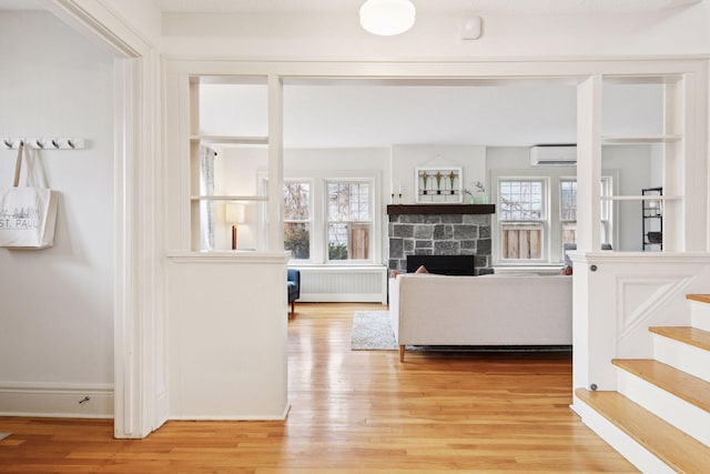 interior space with baseboards, light wood-style floors, stairway, radiator, and a wall mounted air conditioner