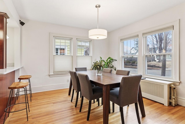 dining area with radiator, light wood-style flooring, and baseboards