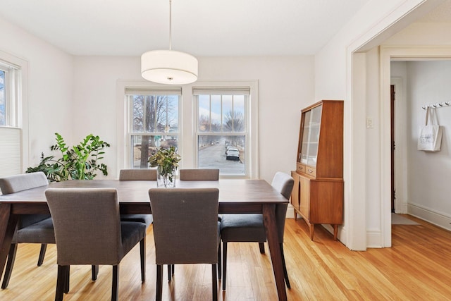 dining space with light wood finished floors and baseboards