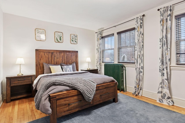 bedroom with radiator heating unit, baseboards, and wood finished floors