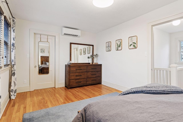 bedroom featuring a wall mounted AC, wood finished floors, and baseboards