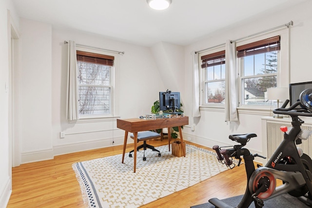 home office featuring baseboards, light wood finished floors, and a healthy amount of sunlight