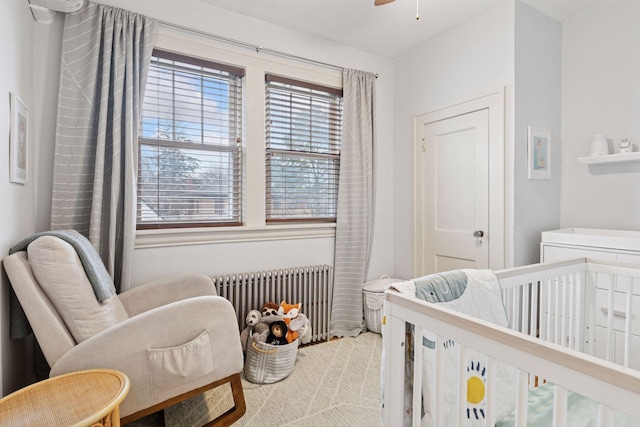 bedroom featuring a nursery area, carpet flooring, and radiator heating unit