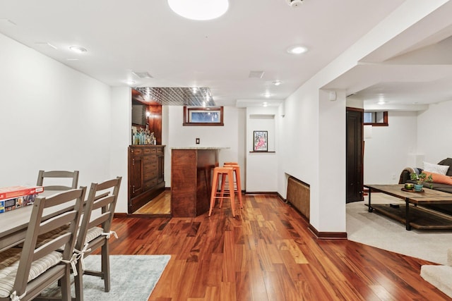 dining room featuring a dry bar, baseboards, wood finished floors, and recessed lighting