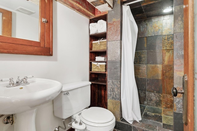 bathroom with stone tile flooring, visible vents, toilet, a sink, and tiled shower