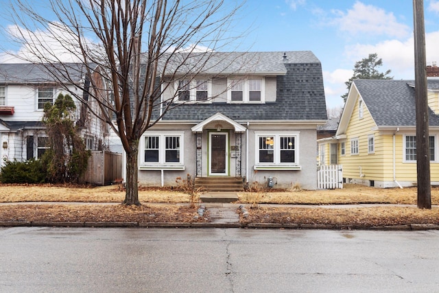 dutch colonial with roof with shingles, fence, and stucco siding