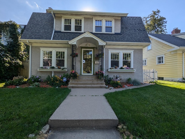 bungalow-style house with a shingled roof, fence, a front lawn, and stucco siding