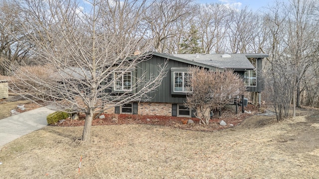 view of front facade featuring brick siding, concrete driveway, and a shingled roof