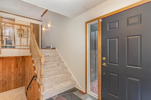 foyer featuring carpet, visible vents, baseboards, stairs, and a textured ceiling