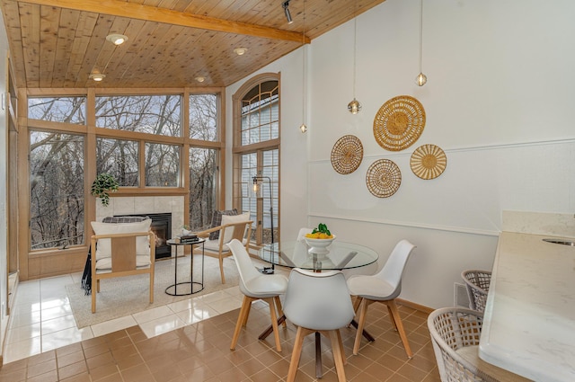 tiled dining space featuring visible vents, beamed ceiling, wooden ceiling, a fireplace, and high vaulted ceiling