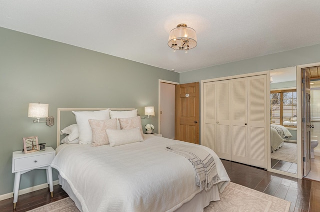 bedroom featuring connected bathroom, baseboards, a closet, a notable chandelier, and wood-type flooring