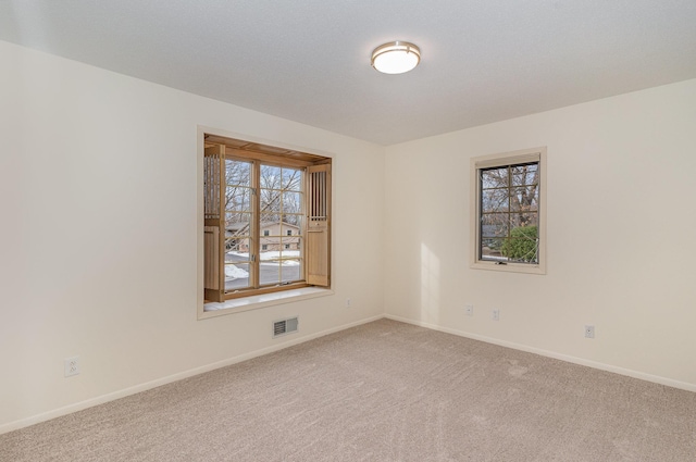 unfurnished room with visible vents, baseboards, and carpet