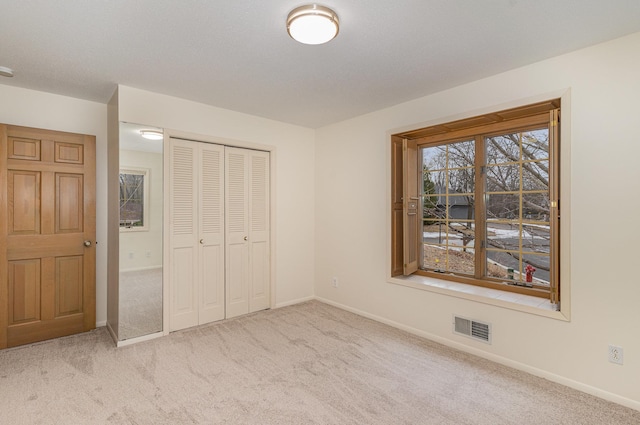 unfurnished bedroom featuring baseboards, visible vents, carpet floors, and a closet