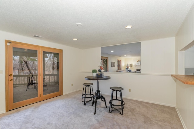 dining space featuring recessed lighting, visible vents, light colored carpet, and a textured ceiling