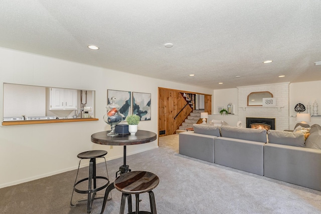 living room with a brick fireplace, stairs, carpet flooring, recessed lighting, and a textured ceiling