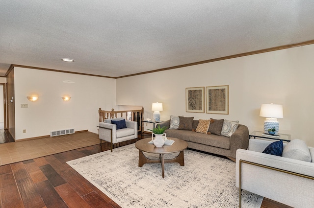 living room with dark wood finished floors, visible vents, a textured ceiling, and ornamental molding