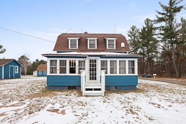 snow covered house featuring a sunroom