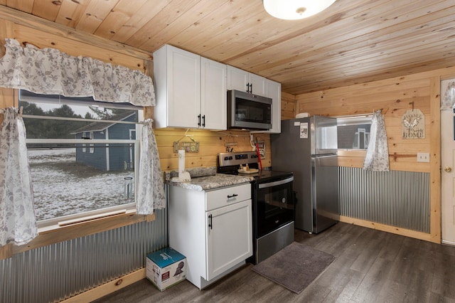 kitchen featuring wooden walls, white cabinets, dark wood-type flooring, and appliances with stainless steel finishes