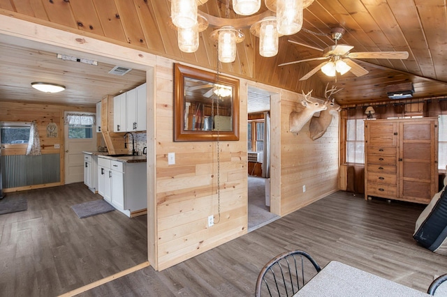 interior space with white cabinetry, dark wood-type flooring, and wood walls