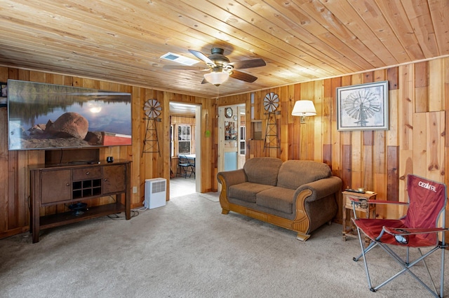 carpeted living room featuring ceiling fan, wood walls, and wooden ceiling