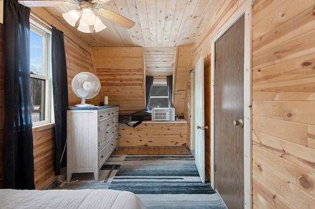 bedroom with cooling unit, wooden walls, dark hardwood / wood-style flooring, and ceiling fan