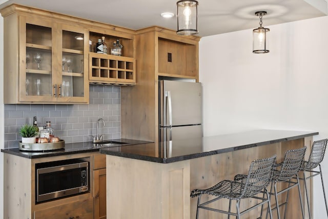 kitchen featuring sink, decorative backsplash, appliances with stainless steel finishes, decorative light fixtures, and a breakfast bar area