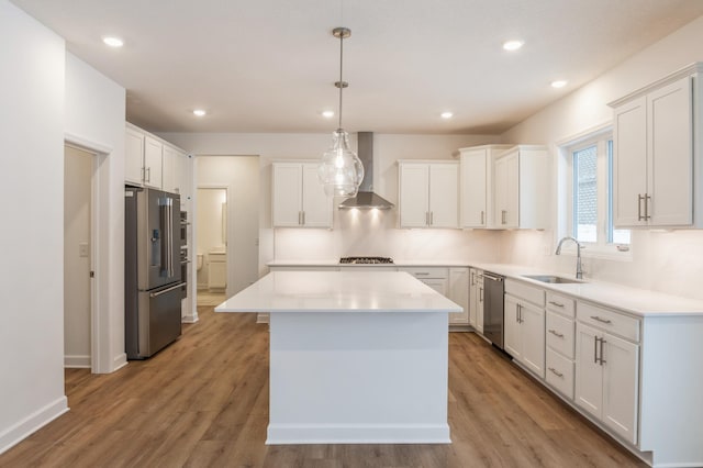 kitchen featuring white cabinetry, stainless steel appliances, wall chimney exhaust hood, and a kitchen island