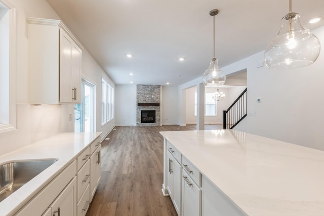 kitchen with plenty of natural light, a stone fireplace, white cabinetry, and hardwood / wood-style flooring