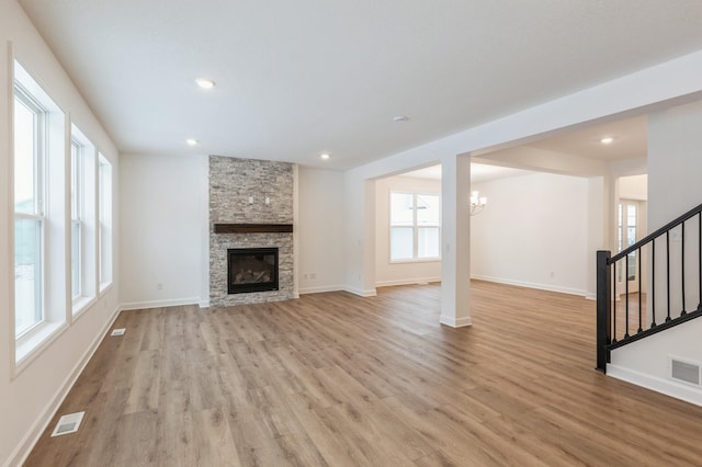 unfurnished living room featuring light hardwood / wood-style floors, an inviting chandelier, and a fireplace