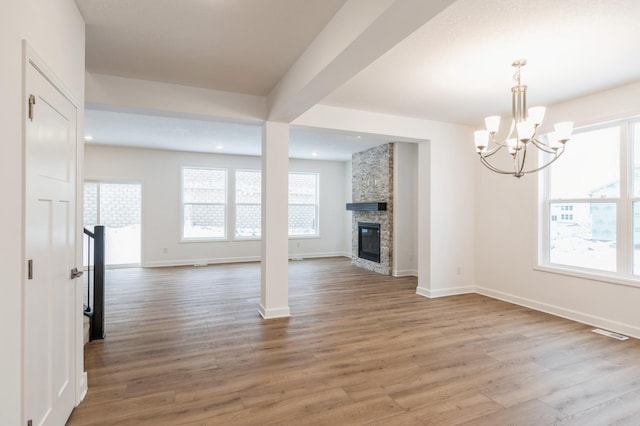 unfurnished living room featuring hardwood / wood-style floors, a fireplace, and a notable chandelier