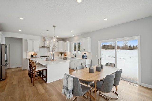 dining room with sink, a textured ceiling, and light wood-type flooring