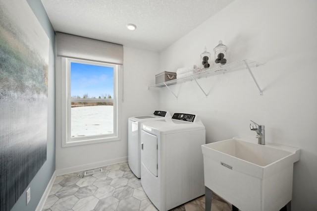 laundry room featuring sink, a textured ceiling, and washing machine and clothes dryer