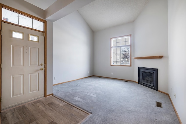 foyer entrance featuring a textured ceiling, hardwood / wood-style flooring, and lofted ceiling