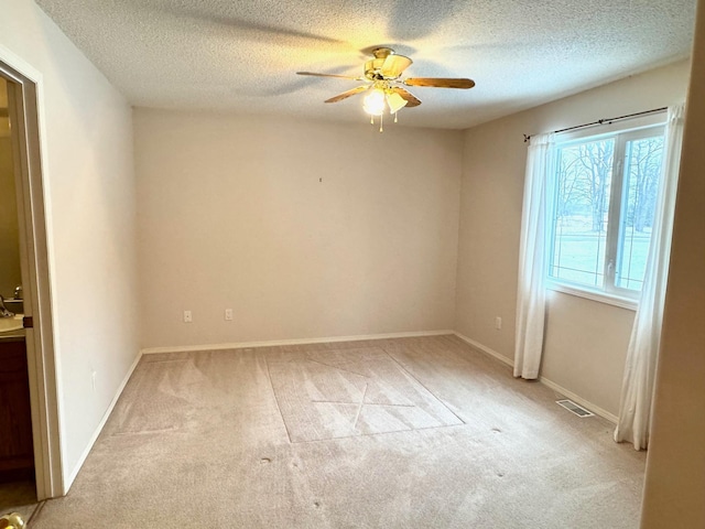 carpeted empty room with ceiling fan and a textured ceiling