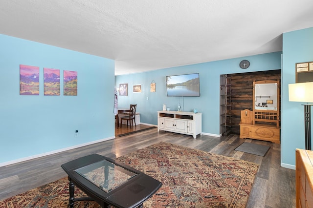 living room with a textured ceiling and dark hardwood / wood-style floors