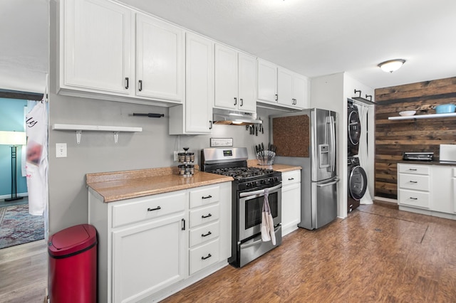 kitchen with white cabinets, stainless steel appliances, stacked washer / dryer, and dark wood-type flooring