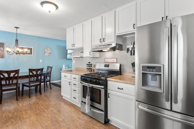 kitchen featuring light wood-type flooring, an inviting chandelier, stainless steel appliances, and white cabinetry