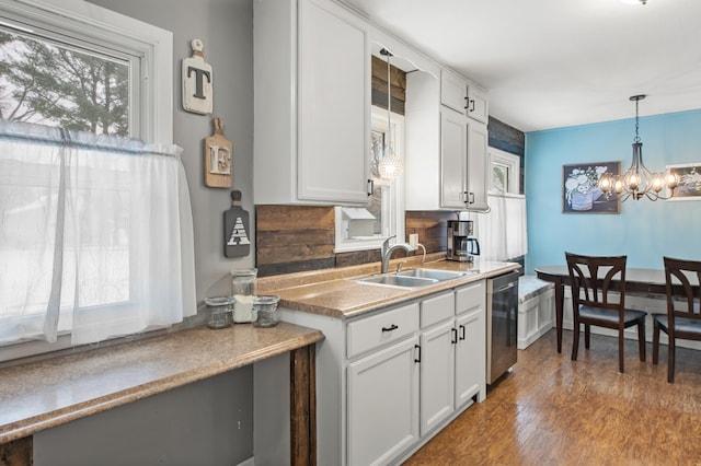 kitchen featuring dishwasher, white cabinets, an inviting chandelier, and sink