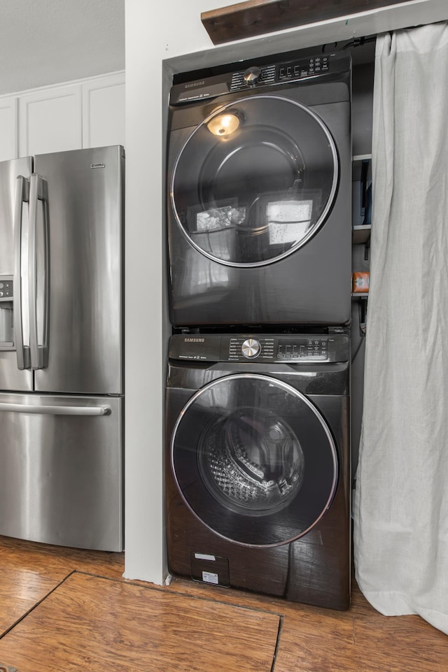 laundry area featuring wood-type flooring and stacked washer and clothes dryer