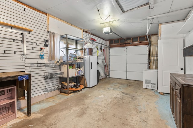 garage featuring white fridge, refrigerator, and a garage door opener