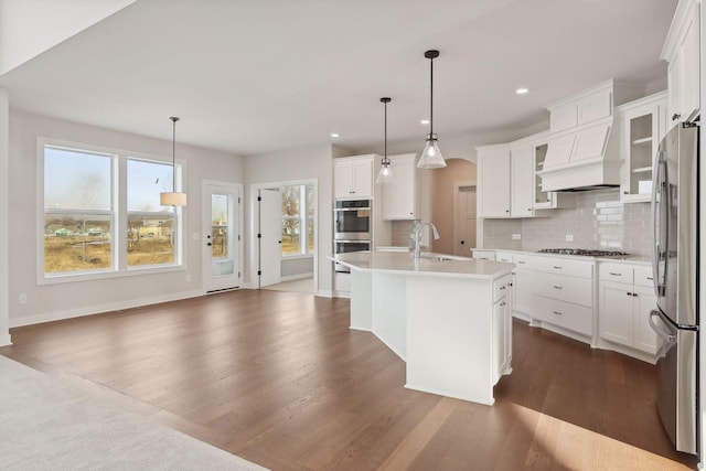 kitchen featuring decorative light fixtures, a center island with sink, white cabinetry, and stainless steel appliances