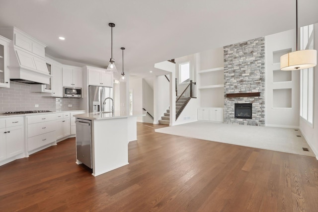 kitchen featuring a kitchen island with sink, dark hardwood / wood-style floors, decorative light fixtures, white cabinetry, and stainless steel appliances